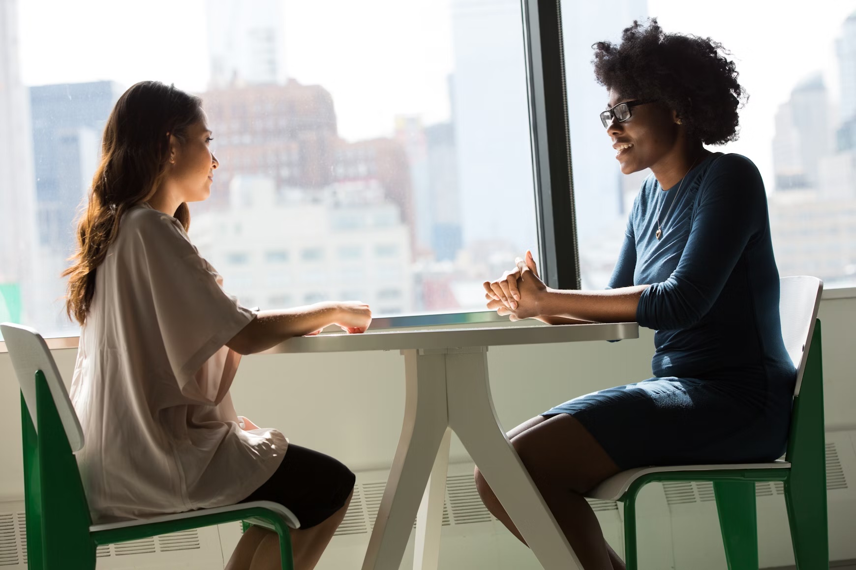 Two women sitting beside table and talking in professional interview setting