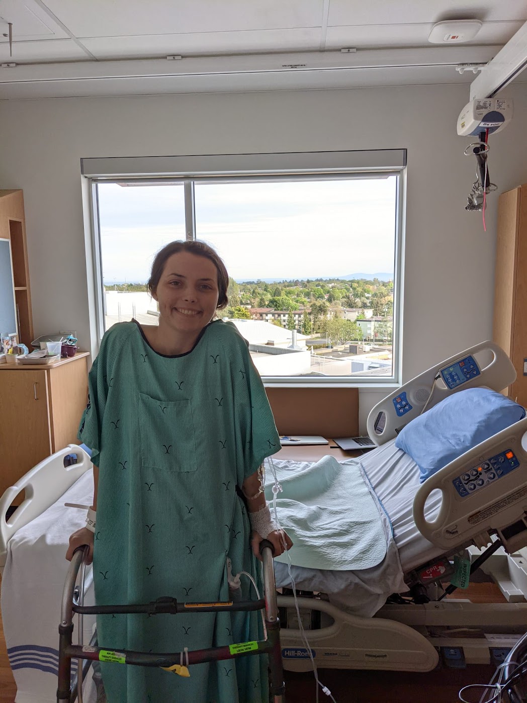 Young woman in hospital gown with walker recovering from ostomy surgery